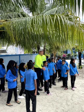 Friendly Maldives representative with local school children under palm trees