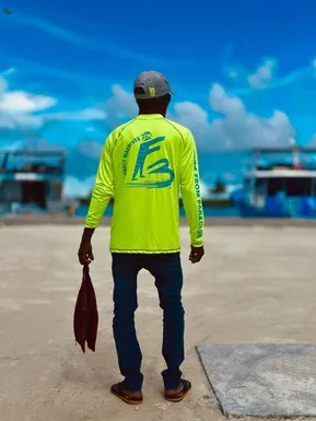Local fisherman at Maldivian harbor in Friendly Maldives shirt holding his catch