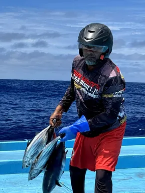 Local Maldivian fisherman holding freshly caught tuna during traditional open sea fishing