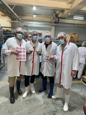 Friendly Maldives team visiting the tuna processing factory, holding FM products and labels