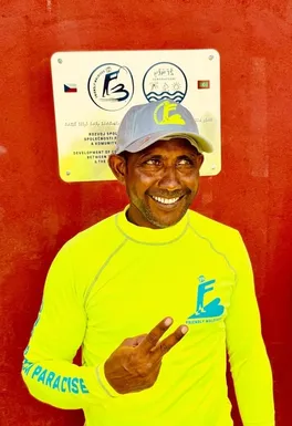 Local resident smiles in front of a commemorative plaque celebrating the partnership between Friendly Maldives and the Gemanafushi fishing community