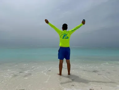 Local man in a Friendly Maldives shirt enjoying ocean view on a tropical beach