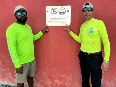 Friendly Maldives representative and local partner standing next to the plaque marking cooperation with the Gemanafushi fishing community