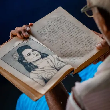 Maldivian man reading a historic book written in Thaana
