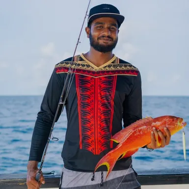 Maldivian fisherman holding a red reef fish caught with traditional pole and line