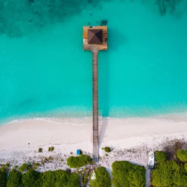 Tropical beach and wooden jetty in the Maldives – land barely above sea level
